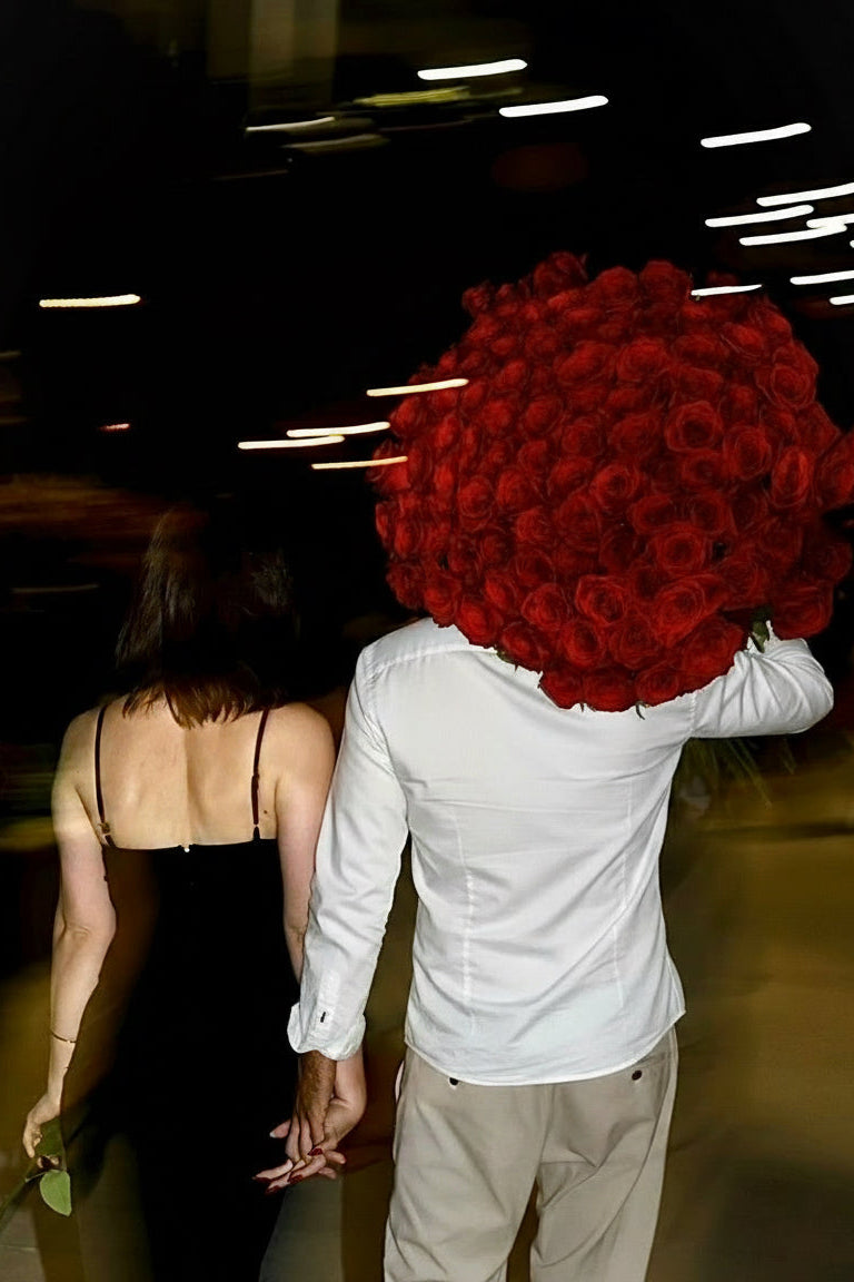 Person holding a large bouquet of red roses, blurred flash photography