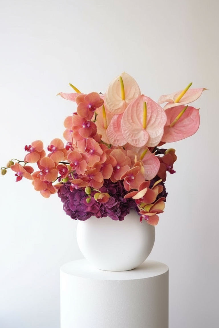 Tall Modern Floral arrangement in a white vase on a white pedestal against a white background